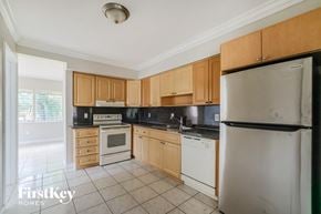 Oakland Park house for rent - a kitchen with wooden cabinets and white appliances
