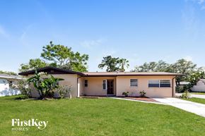 Tampa house for rent - a small tan house with a lawn and a driveway