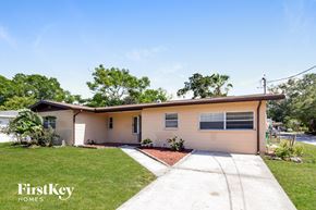 Tampa house for rent - a small tan house with a sidewalk and grass