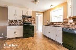Kansas City house for rent - a kitchen with white cabinets and black appliances and a brick wall