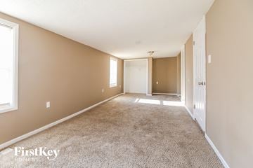 Kansas City house for rent - a spacious living room with carpet and a door to a hallway