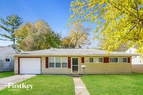 Indianapolis house for rent - the front of a yellow house with a green lawn and trees