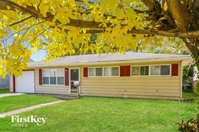 Indianapolis house for rent - the front of a yellow house with a yard and a tree