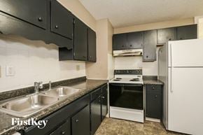 Indianapolis house for rent - a kitchen with black cabinets and white appliances and a sink