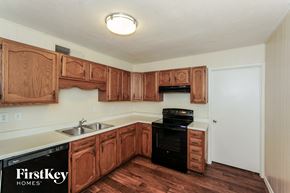 Grand Prairie house for rent - a kitchen with wooden cabinets and black appliances and a sink