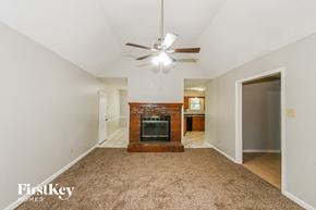 Memphis house for rent - an empty living room with a fireplace and a ceiling fan