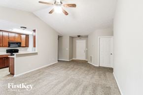 Gainesville house for rent - an empty living room with a ceiling fan and a kitchen