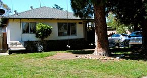 Campbell triplex for rent - Entrance view of a white house with green trim and brick siding a 2 car entrance driveway Prodesse Property Group 1070 & 1072 Arroyo Seco Drive Campbell, CA 95008