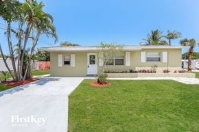 Oakland Park house for rent - a beige house with a lawn and palm trees
