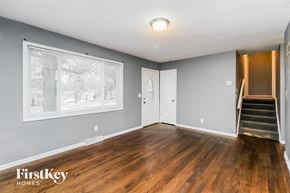 Kansas City house for rent - A spacious room with wooden floors and a staircase leading to another room.