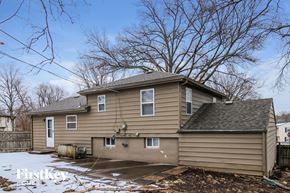 Kansas City house for rent - A house with a brown siding and a white door is surrounded by bare trees.