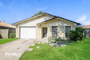 Garland house for rent - a small tan brick house with a white garage door