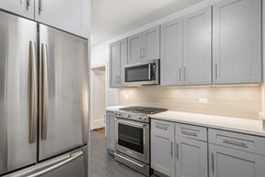 Chicago apartment for rent - a kitchen with white cabinets and stainless steel appliances