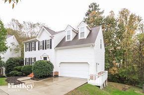 Greensboro house for rent - A white house with a garage is surrounded by trees.