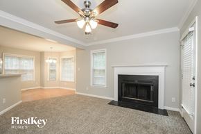 Greensboro house for rent - A spacious living room with a fireplace and a ceiling fan.
