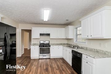 Sugar Hill house for rent - A kitchen with white cabinets and a black fridge.