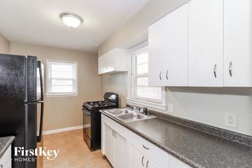 Memphis house for rent - a kitchen with white cabinets and black counter tops and a black refrigerator