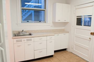 Chicago apartment for rent - a kitchen with white cabinets and a sink and a window