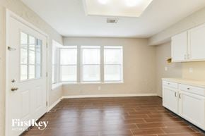 Spring house for rent - an empty kitchen with white cabinets and a window