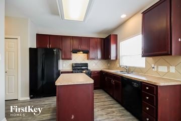 Spring house for rent - A kitchen with dark wood cabinets and a black refrigerator.