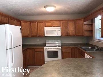 Gainesville house for rent - A kitchen with wooden cabinets and a white refrigerator.