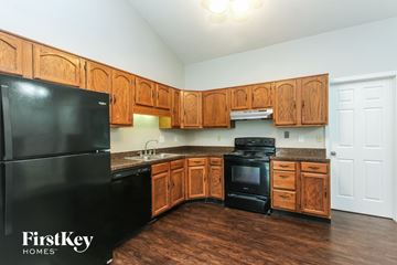 Indianapolis house for rent - A kitchen with wooden cabinets and a black fridge.