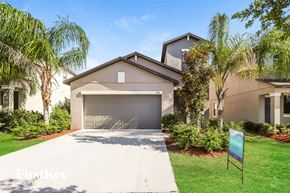 Wimauma house for rent - A house with a garage is surrounded by greenery.