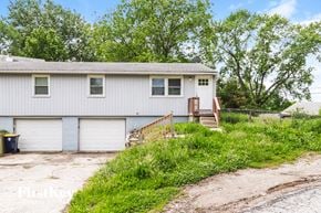 Kansas City house for rent - a white house with two garage doors and a driveway