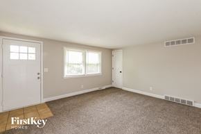 Kansas City house for rent - a bedroom with a carpeted floor and a door and two windows