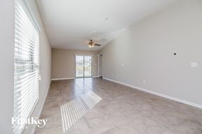 Wimauma house for rent - A spacious room with a fan and sliding glass doors.