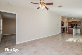 Wimauma house for rent - A spacious living room with a ceiling fan and a kitchen in the background.