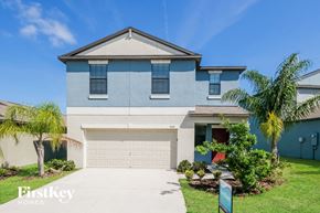 Wimauma house for rent - A blue house with a white garage door and a sign that says "FirstKey Homes".