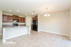 Wimauma house for rent - A kitchen with a black refrigerator and wooden cabinets.