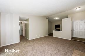 Indianapolis house for rent - A spacious room with a carpeted floor and a door on the right side.