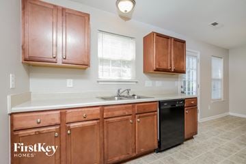 Winston-Salem house for rent - a kitchen with wooden cabinets and a sink and a window