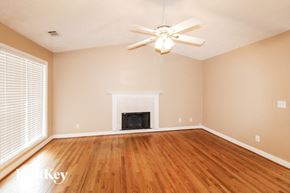 Flowery Branch house for rent - an empty living room with a fireplace and a ceiling fan