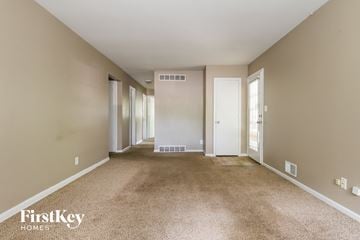 Kansas City house for rent - a spacious living room with carpet and a door to a hallway