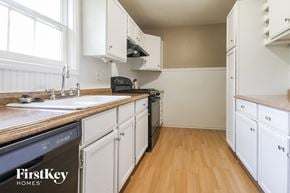 Kansas City house for rent - a kitchen with white cabinets and a sink and a stove