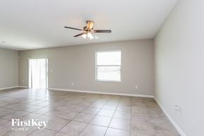 Wimauma house for rent - A spacious room with a ceiling fan and two windows.