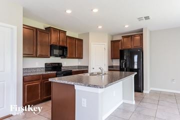Wimauma house for rent - A kitchen with brown cabinets and a black fridge.