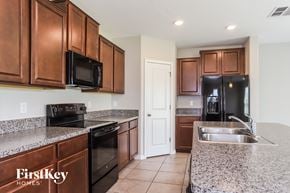 Wimauma house for rent - A kitchen with brown cabinets and a black fridge.