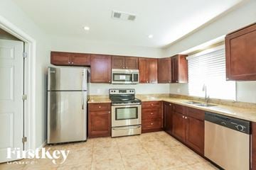 Tempe house for rent - A kitchen with brown cabinets and a stainless steel refrigerator.