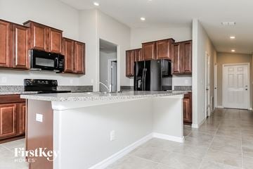 Wimauma house for rent - a kitchen with wooden cabinets and a granite counter top