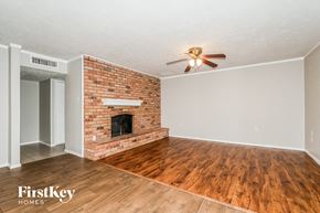 The Colony house for rent - A room with a brick fireplace and wooden flooring.