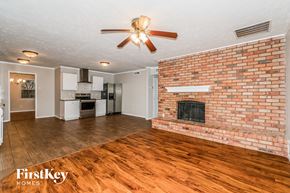 The Colony house for rent - A living room with a brick fireplace and wooden floors.