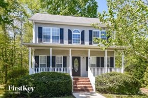 Winston-Salem house for rent - A white house with a black door and windows is surrounded by greenery.