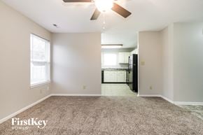 Indianapolis house for rent - an empty living room with a ceiling fan and a kitchen