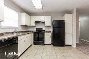 Indianapolis house for rent - a kitchen with white cabinets and black appliances