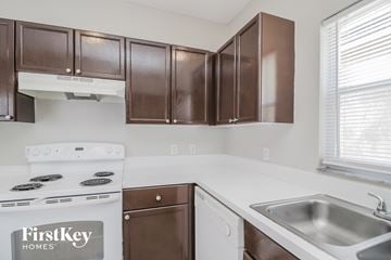 Orlando house for rent - A kitchen with brown cabinets and a stove that says FirstKey Homes.