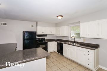 Memphis house for rent - A kitchen with white cabinets and a black fridge.